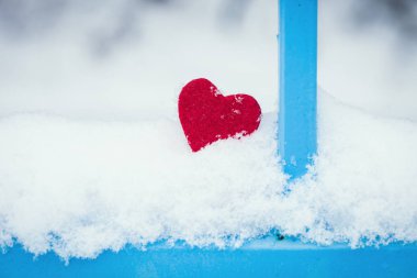 Mavi çit tarafından karda kırmızı kalp 