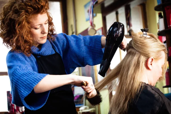 Giovane donna nel suo studio di capelli con cliente — Foto Stock
