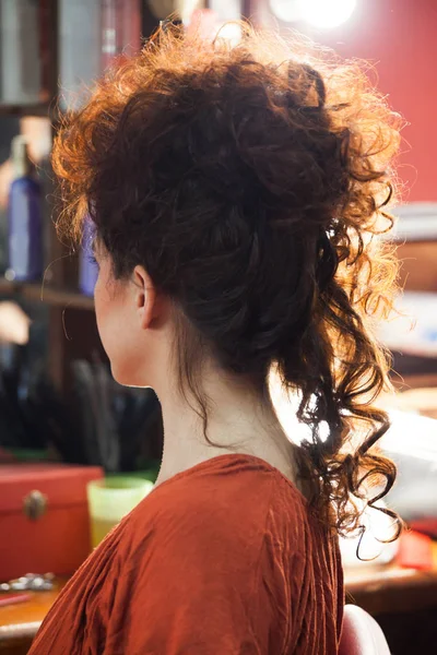 Woman with raised long curly hair at hairdresser — Stock Photo, Image