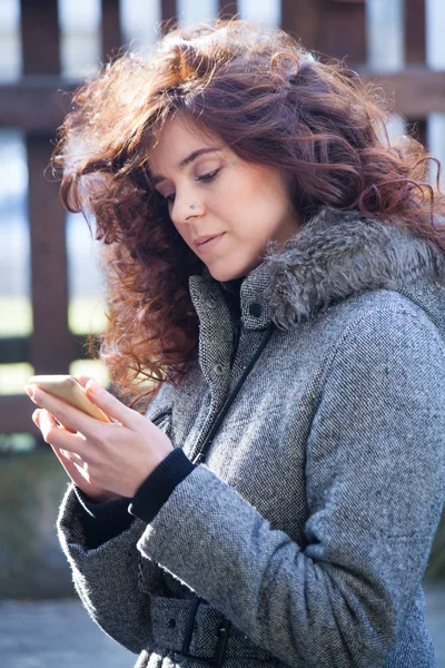 Кучеряве волосся жінка з смартфоном на відкритому повітрі — стокове фото