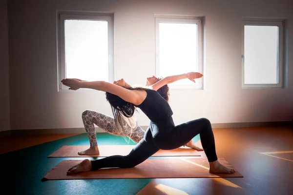 Två unga kvinnor gör yoga inomhus — Stockfoto