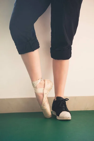 Tanečník dívka nohy v teniskách a baletní boty closeup — Stock fotografie