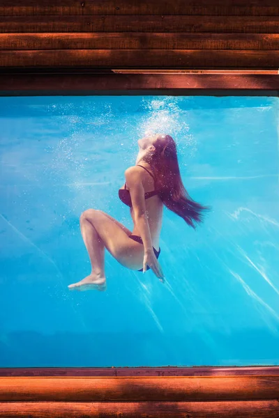 Chica en la piscina bajo el agua a través del vidrio —  Fotos de Stock