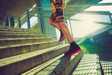 Şehirde açık merdivenlerden koşan genç adam