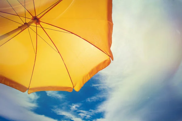 Guarda-chuva amarelo contra o céu azul com nuvens — Fotografia de Stock