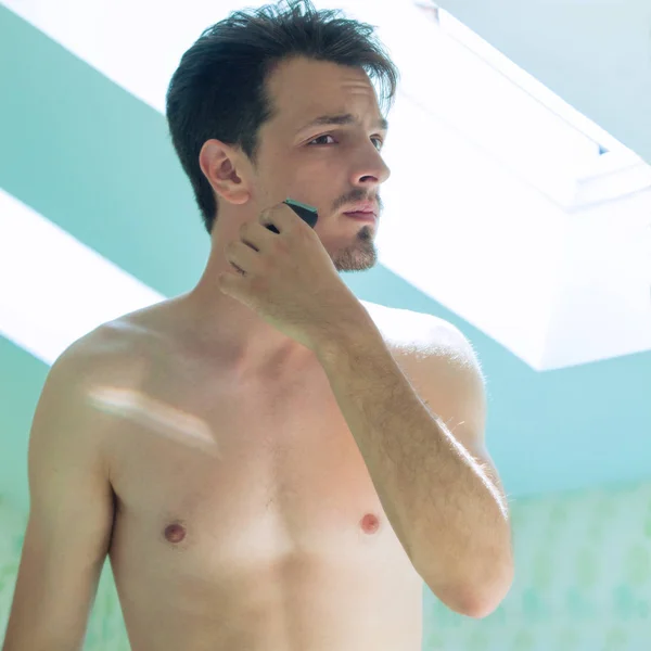 Junger Mann schneidet Bart vor Spiegel — Stockfoto