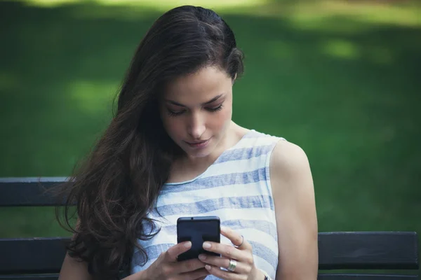 Девушка в городском парке с помощью смартфона — стоковое фото