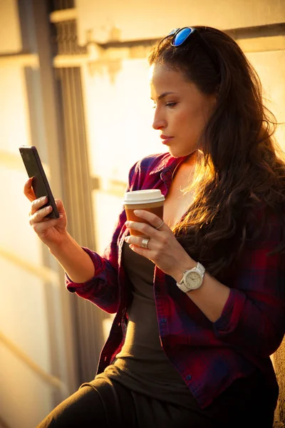 Chica en la ciudad con teléfono inteligente y café para llevar —  Fotos de Stock