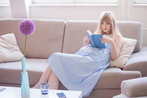 Беременная женщина читает книгу в квартире — стоковое фото