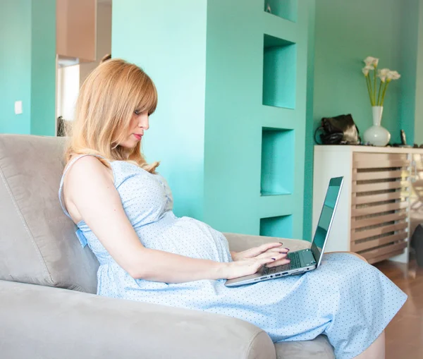 Těhotná žena s laptopem v bytě — Stock fotografie