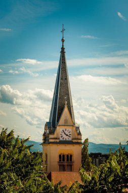 Catholic church clock tower  among tree crowns  clipart