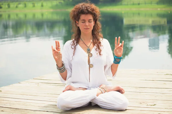 Mujer joven practica yoga al aire libre junto al lago — Foto de Stock