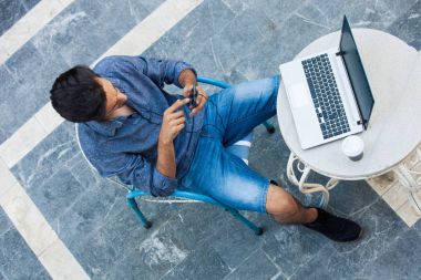 dizüstü bilgisayar ve smartphone terasından çalışan genç adam