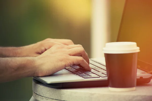 Hombre manos usando el ordenador portátil y café para ir al aire libre primer plano —  Fotos de Stock