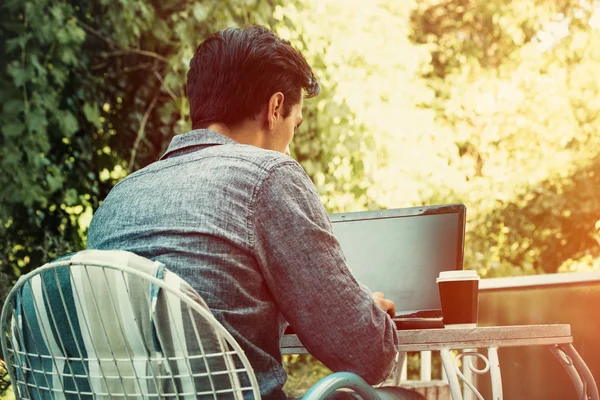 Joven trabajando en línea en portátil vista trasera al aire libre —  Fotos de Stock