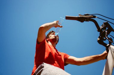 genç adam bir bisiklet içecek su shotpause aşağıdan, 