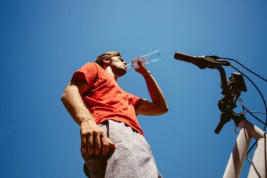 genç adam bir bisiklet içecek su atış aşağıdan