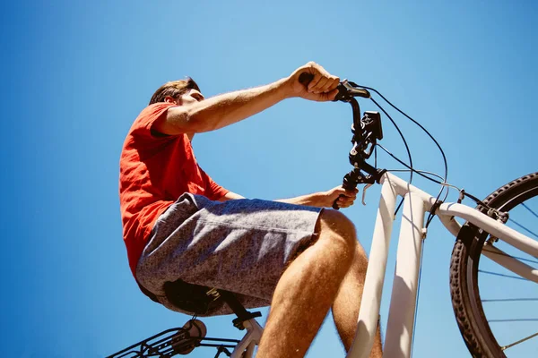 Joven montar en bicicleta desde abajo tiro — Foto de Stock