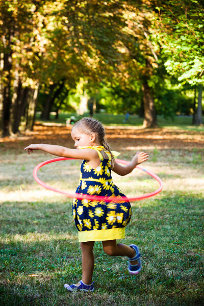 little girl play with hula hoop in park