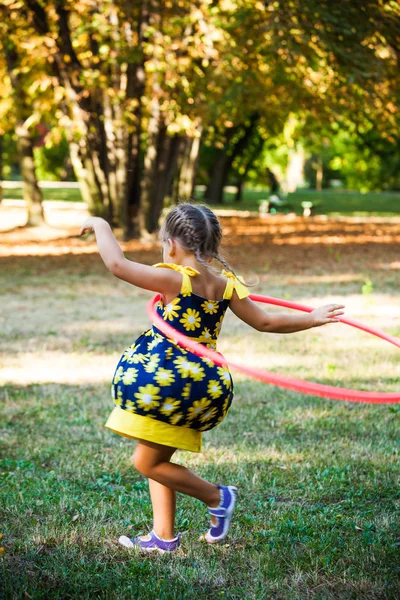 Kleines Mädchen spielt mit Hula-Hoop-Reifen im Park — Stockfoto