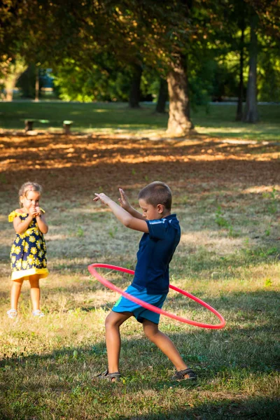 Pequeno menino jogar com hula aro no parque — Fotografia de Stock