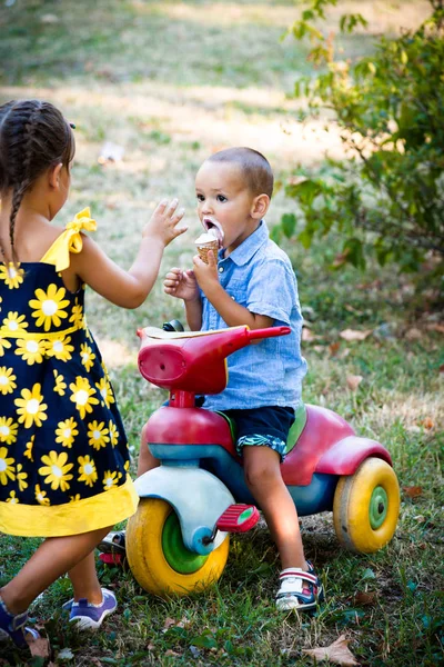 küçük çocuk onun sist ise küçük üç tekerlekli bisiklet üzerinde dondurma oturup yemek