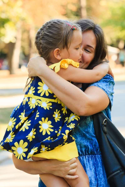 Мила маленька дівчинка обіймає матір на відкритому повітрі в парку — стокове фото