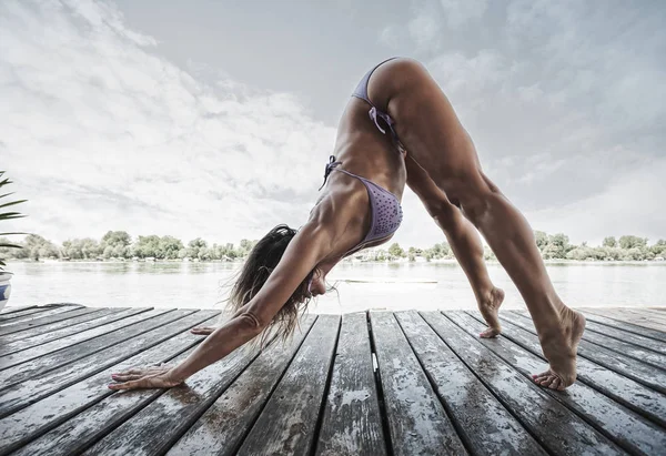 Femme adulte faisant du yoga en bikini sur radeau de rivière en bois — Photo