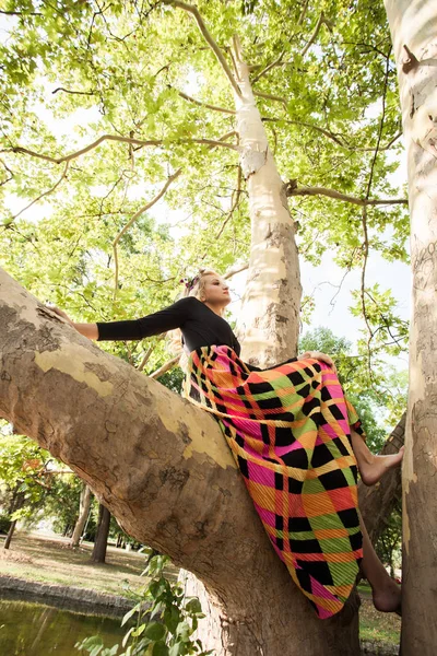 Boho Mädchen in langen bunten Kleid sitzen auf Baum im Park Sommertag — Stockfoto