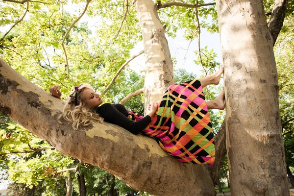 Boho Mädchen in langen bunten Kleid liegen auf Baum im Park Sommertag — Stockfoto