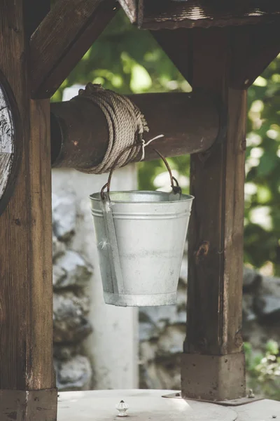 metal water bucket on wooden well closeup