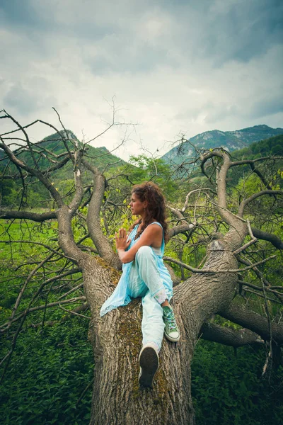 Joven mujer practica yoga al aire libre en enorme árbol caído en el monte —  Fotos de Stock