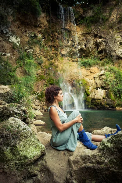 Jonge vrouw praktijk yoga buiten op de rotsen door de waterval — Stockfoto