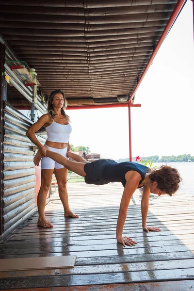 Vrouw fitness instructeur bijstaan van jonge vrouw in oefening overtreffen — Stockfoto
