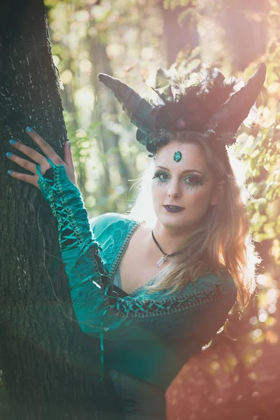 fantasy  fairy with horns in forest among  trees and branches