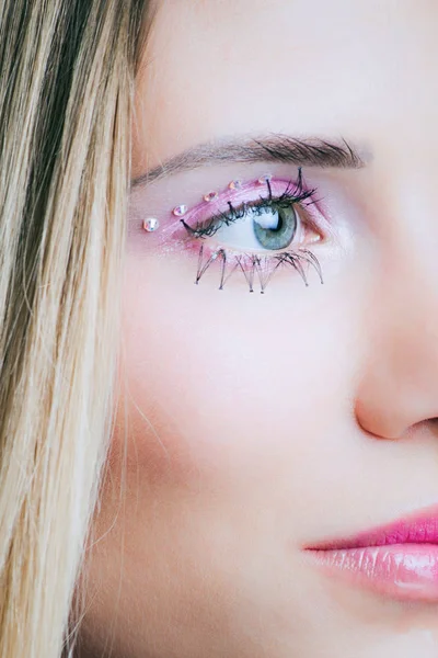 Primer plano de la cara de la mujer con pestañas de maquillaje rosa y cristales — Foto de Stock