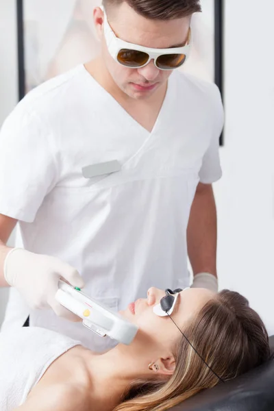 Vrouw tijdens gezicht lasertherapie in cosmetica — Stockfoto