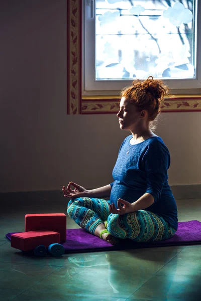 Rossa testa incinta giovane donna in classe di yoga al coperto — Foto Stock