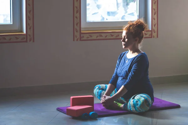 Rossa testa incinta giovane donna in classe di yoga al coperto — Foto Stock
