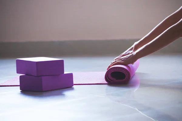 Donna rotolamento tappetino yoga indoor shot luce naturale — Foto Stock