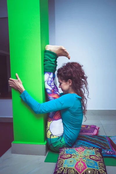 Молодая женщина практикует йогу растягиваясь против колонны внутри помещения — стоковое фото