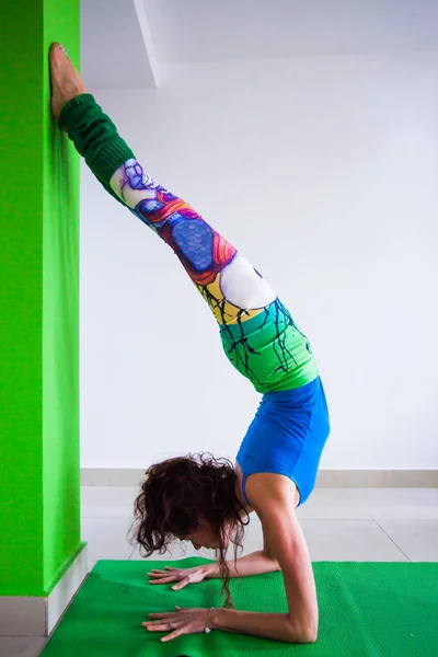 Frau übt Handstand gegen Wand Yoga-Kurs drinnen — Stockfoto