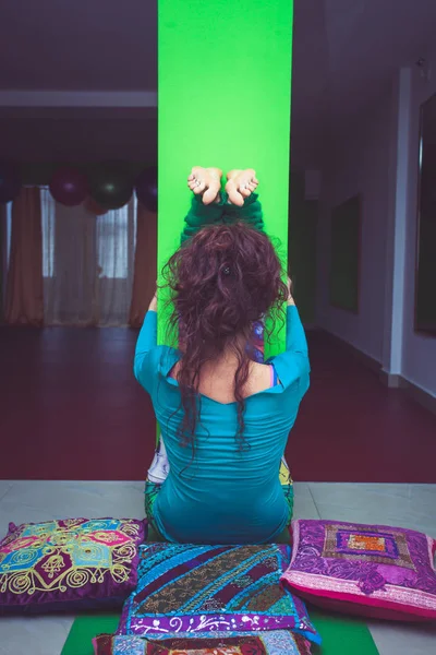 Молодая женщина практикует йогу растягиваясь против колонны внутри помещения — стоковое фото