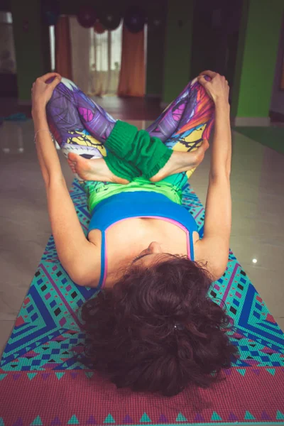 Giovane donna sdraiata sul tappeto con le gambe in posizione di loto tiro al coperto — Foto Stock