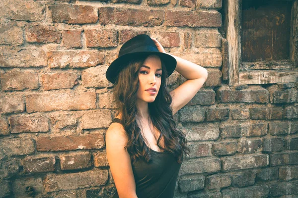 Joven mujer de moda con sombrero de pie en frente de la vieja casa abandonada —  Fotos de Stock