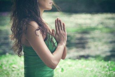 Park manzaralı bir yerde yoga yapan genç bir kadın.