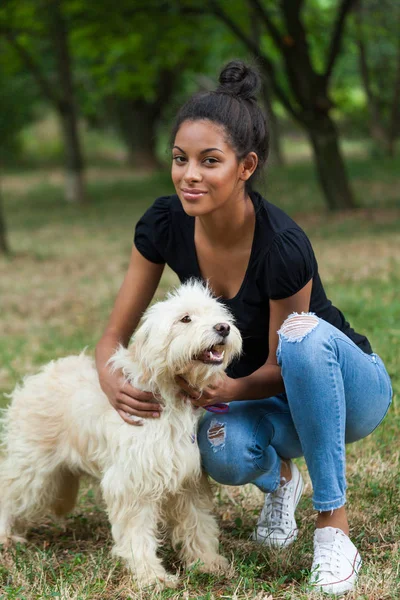 Leende ung svart kvinna leka med sin hund i parken — Stockfoto