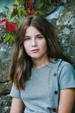 Mavi gözlü genç kız portresi taş duvara karşı.