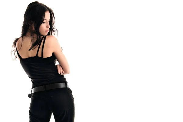 年轻迷人的女人穿着黑色的背心和黑色的牛仔裤背向镜头轮廓面对着白色的背景复制空间 — 图库照片