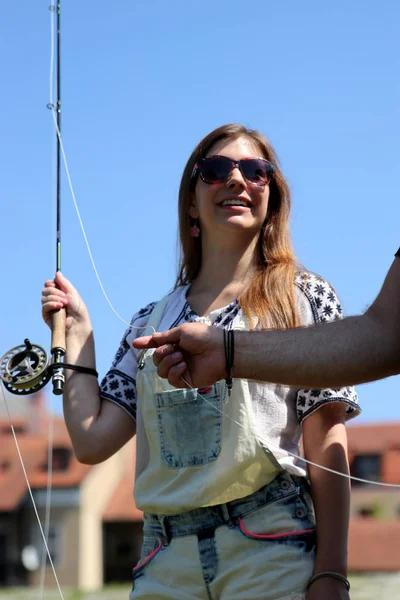 Jovem mulher com brotos de verão e dungarees enquanto pesca — Fotografia de Stock